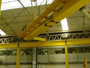 Ponte rolante amarela Demag instalada no interior de galpão industrial